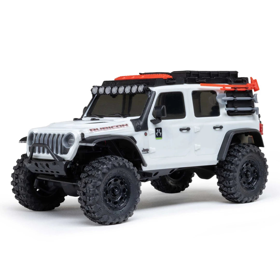 A white Axial SCX30 Jeep Wrangler JLU 1/30 RTR Rock Crawler featuring black tires, a black roof rack with orange accents, and a black front bumper, photographed on a clean white background.