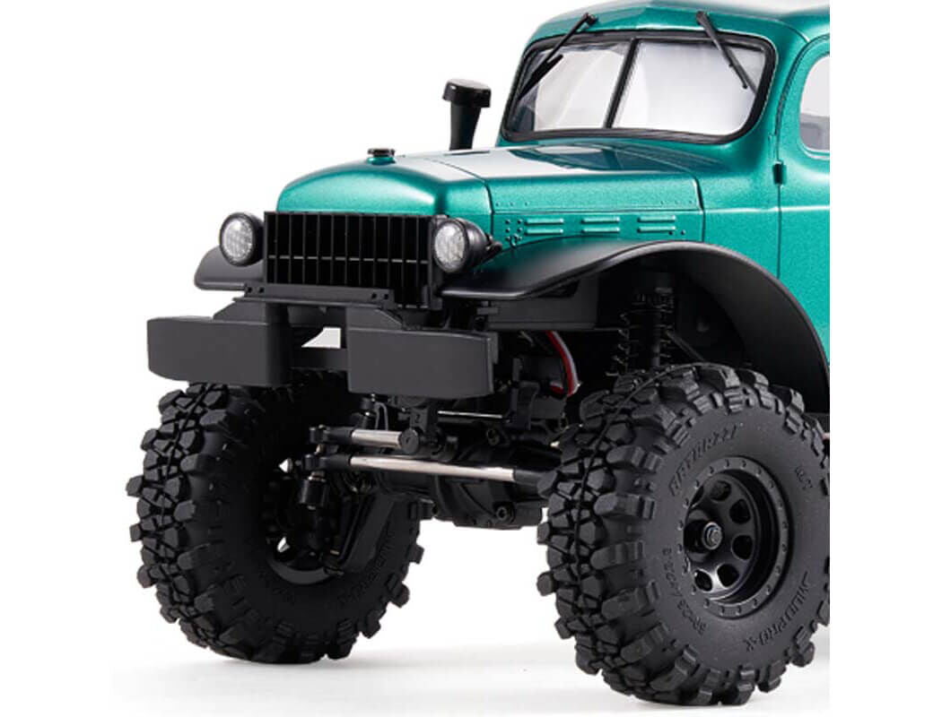 A Green FCX24 Power Wagon Brushless RC Crawler front bumper close up with large tires on a white background