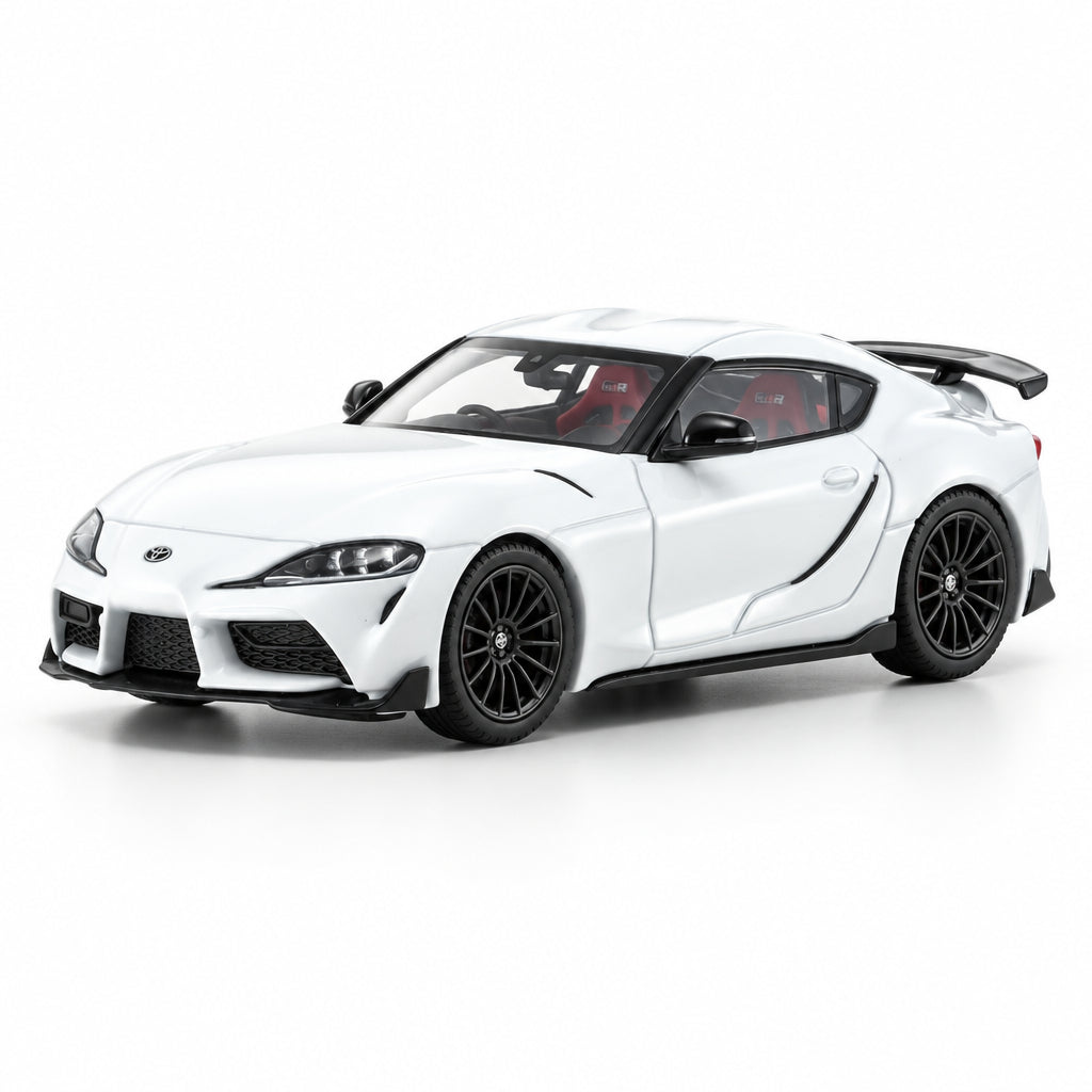 A white die-cast model of a Toyota Supra GTR sports car with black wheels, a black rear spoiler, and red interior seats, photographed on a clean white background.