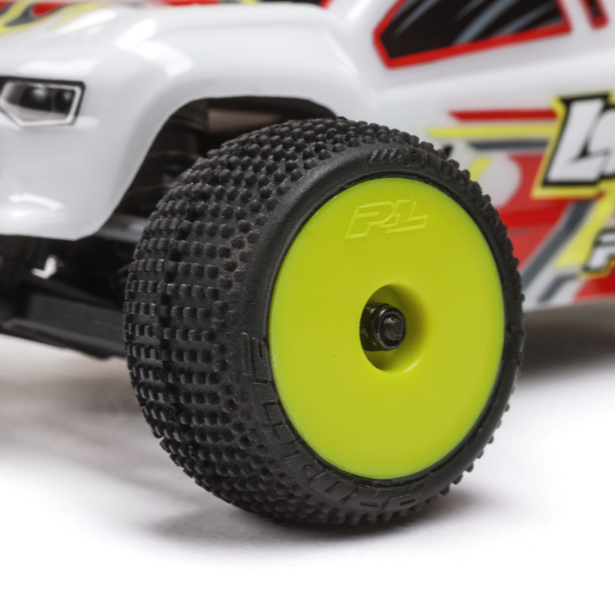 Close-up of a toy car wheel with a green rim and black tread pattern on a white background.