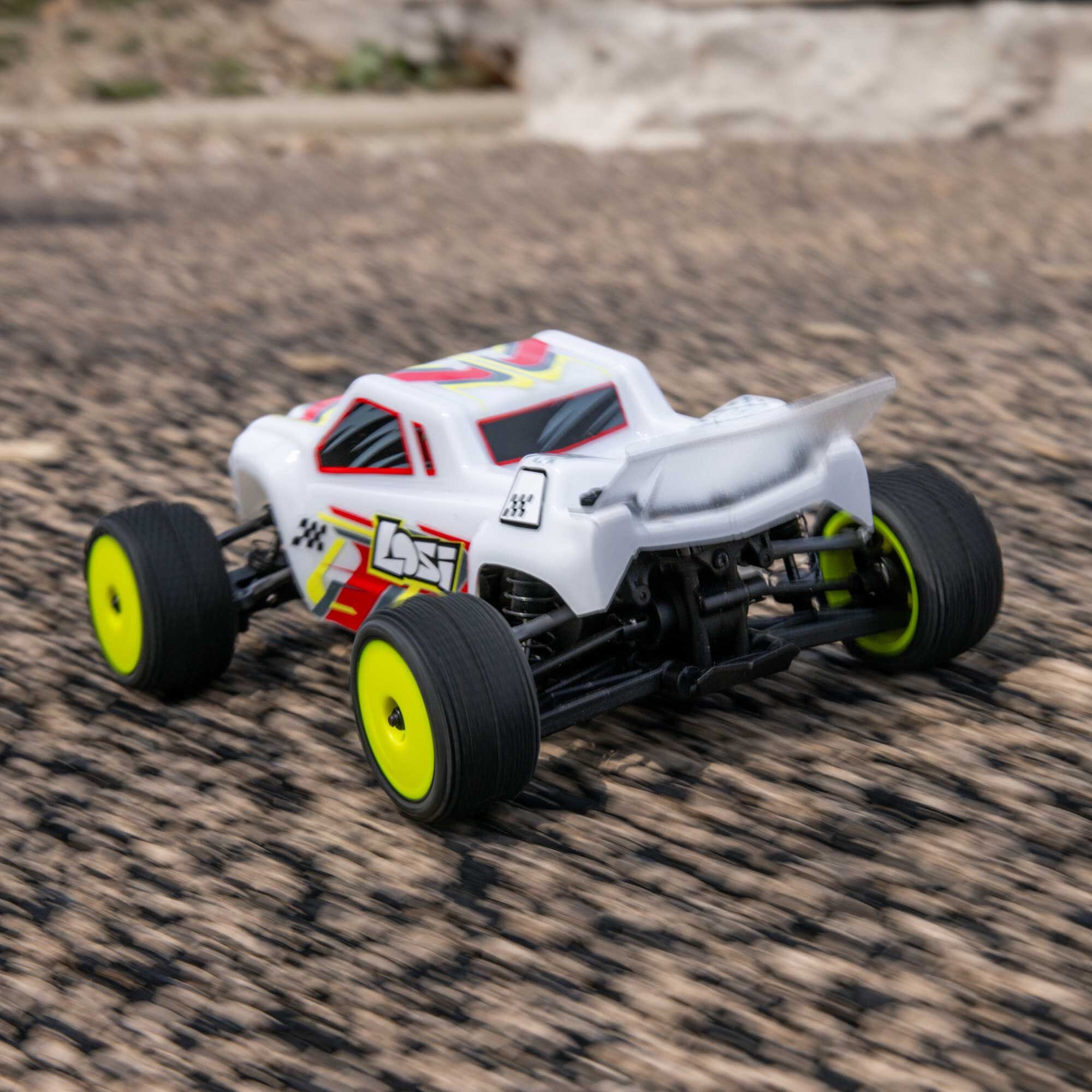 White remote control car with yellow wheels on a textured surface