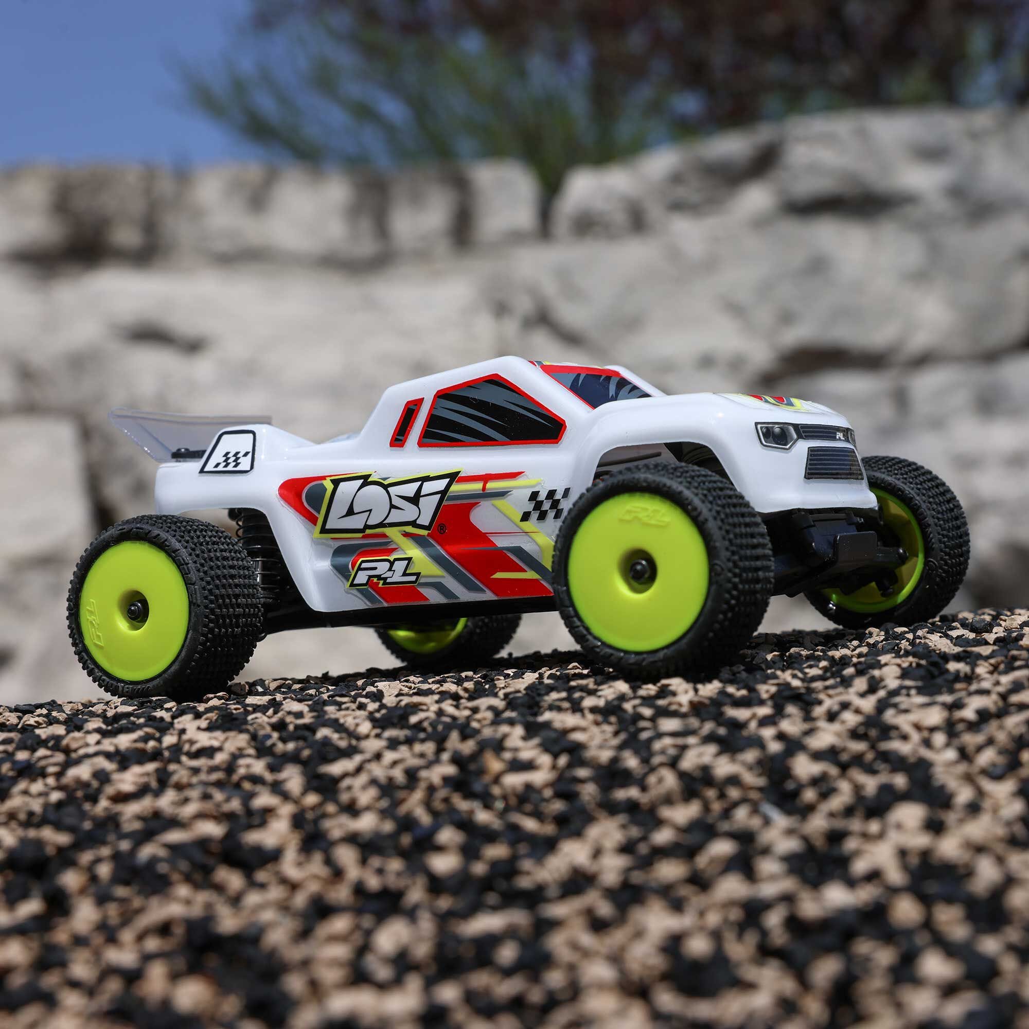 Toy off-road vehicle with green wheels on a rocky surface