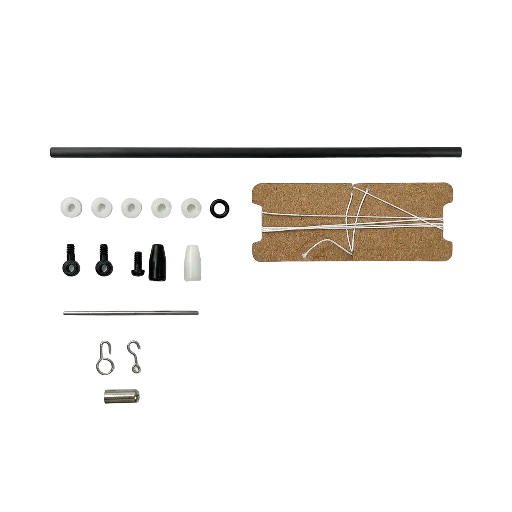 A flat-lay view of a DIY craft kit containing a black rod, a brown cardboard template with white string, and various small black and white hardware pieces on a light gray background.