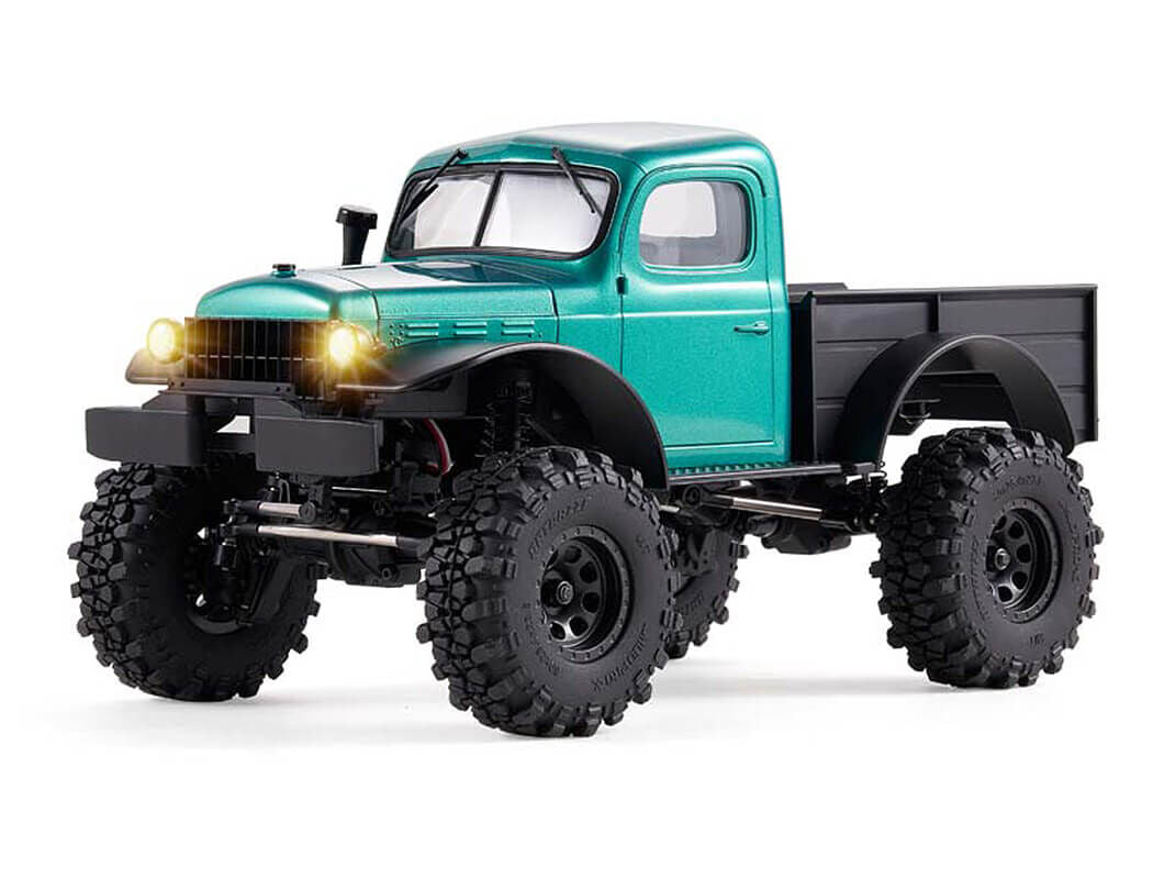 A Green FCX24 Power Wagon Brushless RC Crawler with large wheels and head light illuminated on a white background