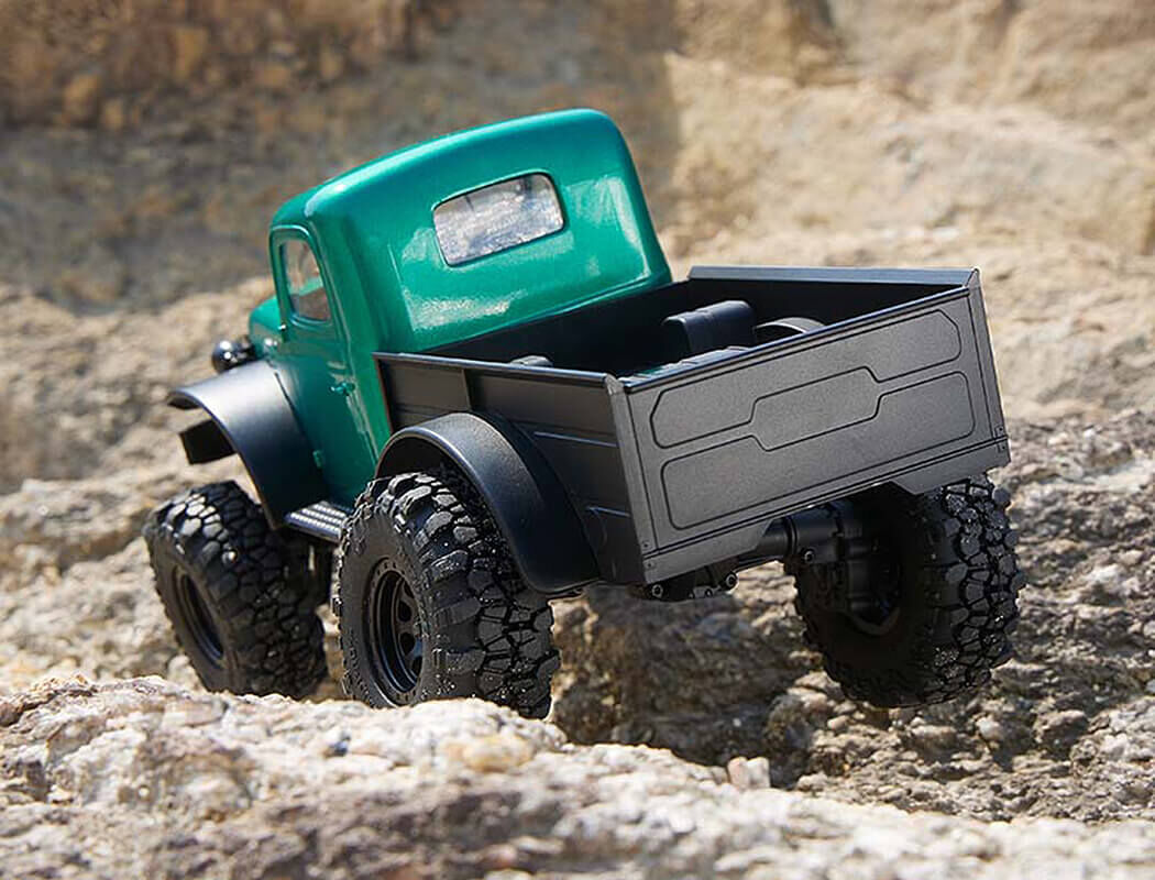 Green FMS Power Wagon RC Crawler with large wheels on a rocky surface
