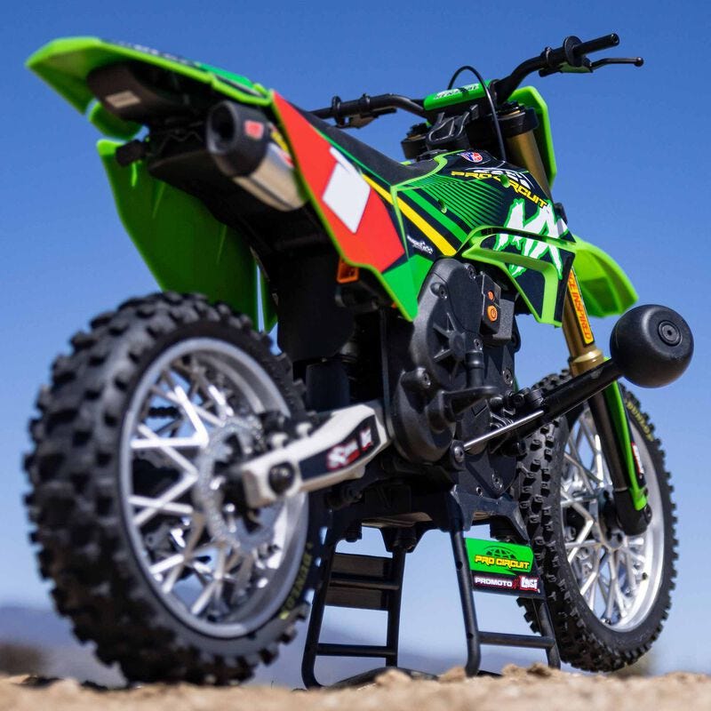 Green dirt bike with red and white accents on a clear blue sky background