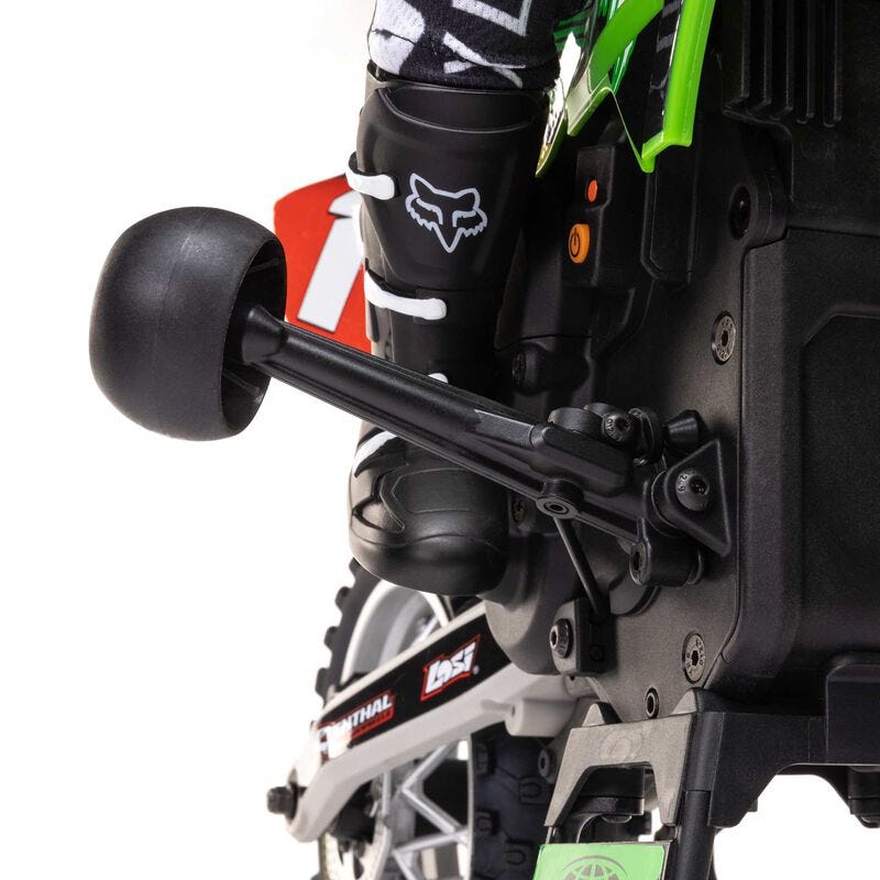 Close-up of a motorcycle with a person wearing black boots featuring a white logo on a white background