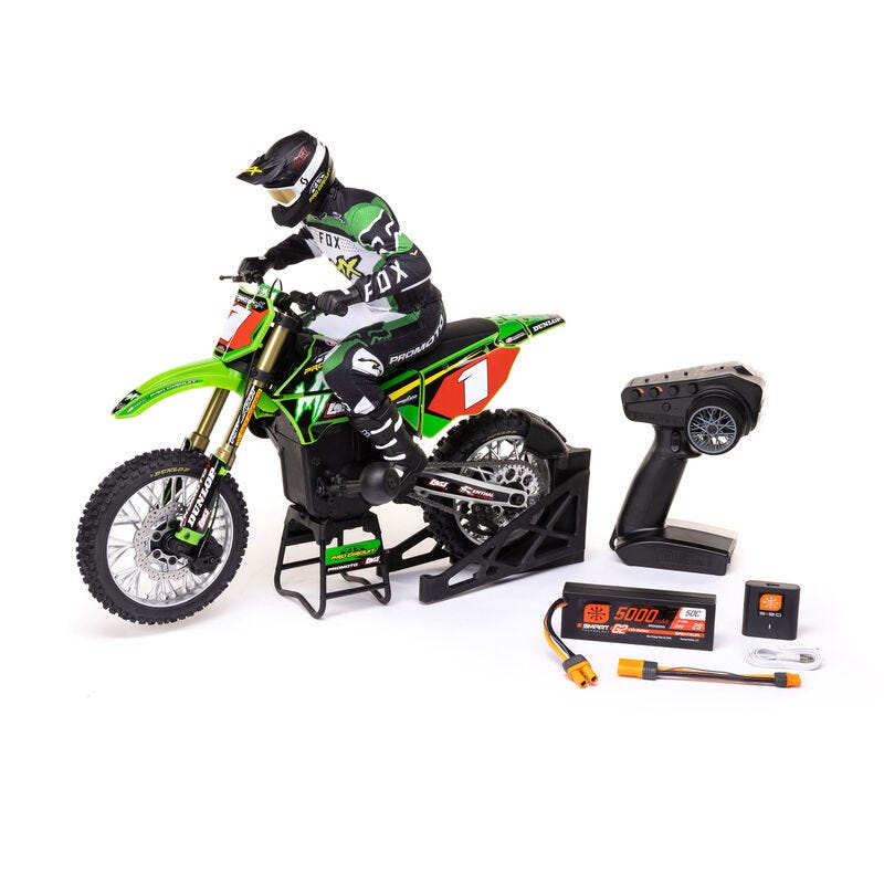 Model of a motocross rider on a green  Losi Promoto-MX 1/4 Dirt Bike with a remote control and battery pack on a white background